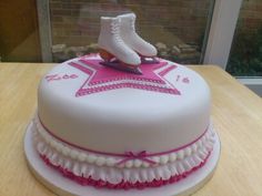 a cake decorated with a pair of ice skates and pink ribbon on the top