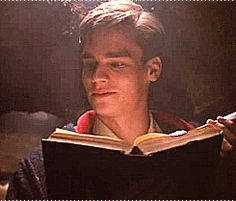 a young man reading a book in the dark