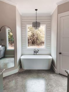 a bathroom with a tub, sink and mirror in it's center wall is shown