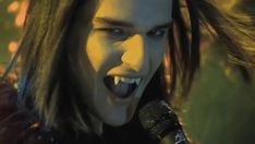 a man with long hair holding a microphone in front of his face and screaming at the camera