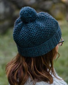 a woman wearing a blue knitted hat with a pom - pom on top