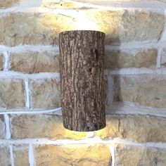 a light that is on the side of a brick wall next to a tree stump