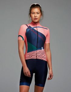 a woman in a pink and blue cycling suit with her hands on her hips, posing for the camera