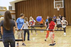 a group of young people standing on top of a hard wood floor next to a basketball court