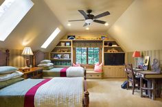 a bedroom with two beds and a desk in front of a tv mounted on the wall