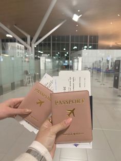 a person holding two passport cards in their hand at an airport terminal with the door open