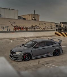 a grey car parked in a parking lot next to a building with graffiti on it