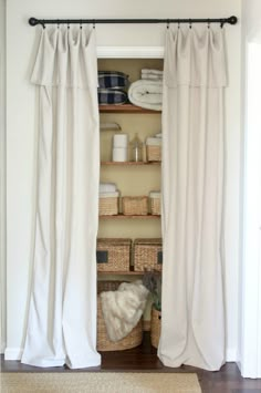 an open closet with white curtains and baskets