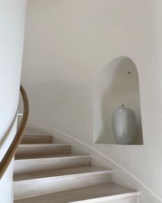 a white vase sitting on top of a set of stairs next to a banister