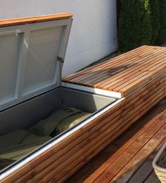 an open wooden box sitting on top of a wooden deck next to a planter