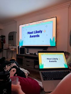 a woman sitting in front of a laptop computer on top of a bed next to a tv