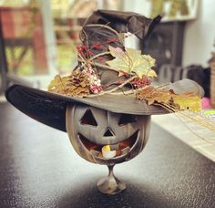 a halloween pumpkin with a hat on it's head sitting on top of a table