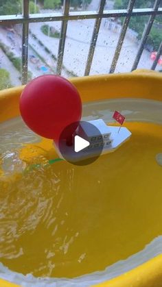 a red balloon floating in a yellow water filled pool with a flag on it's tip