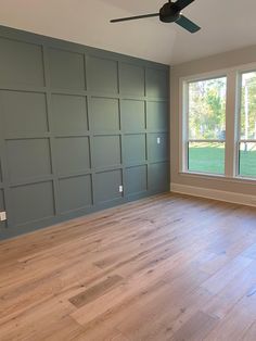 an empty room with wood floors and large windows in the center, painted blue gray