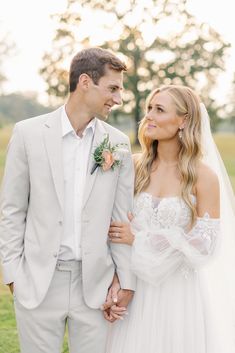 a bride and groom standing together in the grass