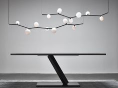 a black table with white balls hanging from it's branches and lights above it