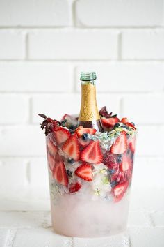 an ice bucket with strawberries in it and a bottle of champagne sitting on top