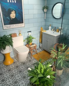 a bathroom with blue tiles and plants in the corner, along with a poster on the wall