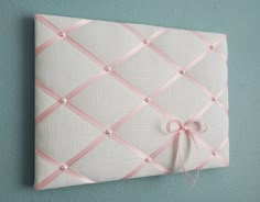 a white wall with a pink ribbon on it and a bow hanging from the side