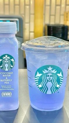 two plastic cups sitting on top of a counter next to each other, one with a drink in it