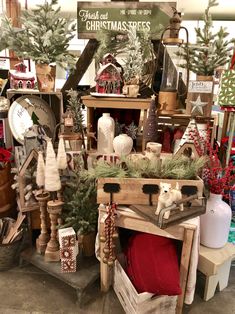 an assortment of christmas trees and other holiday decorations in a store display area with wooden crates