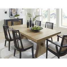 a dining room table with chairs and a bowl of fruit on the table in front of it