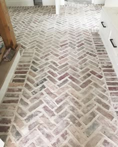 an old brick floor in a bathroom with white cabinets and drawers on either side of it