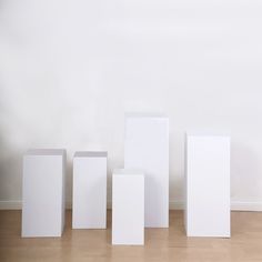 four white boxes are lined up against the wall in an empty room with hard wood flooring