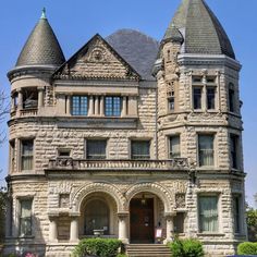 an old stone building with two towers on the top and one at the bottom, in front of a blue car