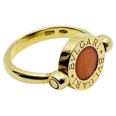 DESIGNER: Bulgari CIRCA: 1990’s MATERIALS: 18K Yellow Gold GEMSTONE: Onyx GEMSTONE 2: Coral WEIGHT: 5.6 grams RING SIZE: 4.5 HALLMARKS: BVLGARI, Madi in Italy, 750 A fun and playful Bulgari flip ring, made of 18k gold, featuring coral and onyx. This spinning ring was inspired by the Roman culture and city’s ability to blend together past and modern styles. Bulgari flip rings collection offers multiple colorful combos of gemstones. The brand suggests treating this ring as a flipping coin to choos Flip Ring, Roman Culture, Spinning Ring, Spinning Rings, Rings Collection, Onyx Gemstone, Van Cleef Arpels, Design Minimalista, Ring Collections