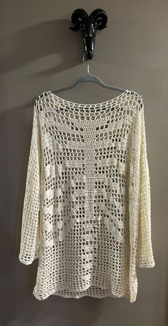 a white crocheted top hanging on a wall