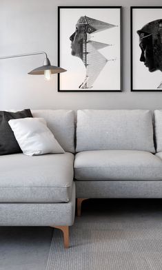 two framed pictures hang on the wall next to a gray couch with white pillows and throw pillows