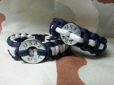 two white and blue paracorte bracelets with us navy seal emblem on them