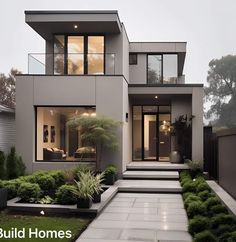 a modern house with lots of windows and plants in the front yard