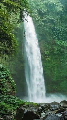 a man standing in front of a tall waterfall