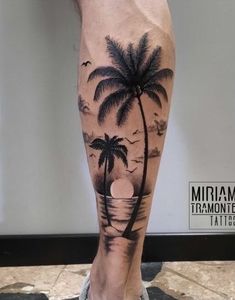 a man's leg with a palm tree and sunset on the beach tattoo design