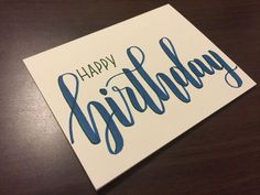 a card with the words happy birthday written on it, sitting on top of a wooden table