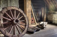 an old wooden wagon wheel sitting on the floor next to other wood and metal items