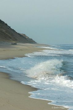 the waves are crashing onto the sandy beach