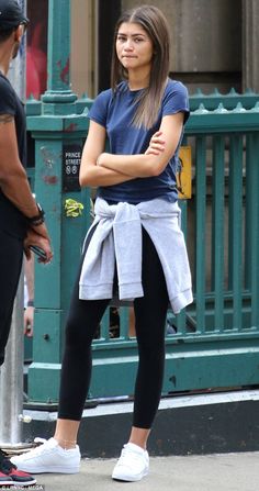 a woman standing on the street with her arms crossed