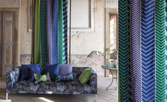 a couch sitting in front of a window covered in blue and green striped curtains next to a table