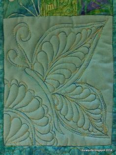 a close up of a quilted wall hanging with flowers and leaves on it's side