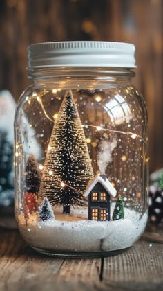 a glass jar filled with snow covered christmas trees and small houses on top of it