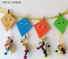 four colorful kites hanging on a string with eyes and nose drawn on them in different colors