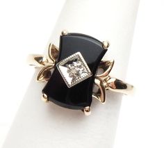 This is such a pretty black onyx ring from the 1950s. The ring has a fancy, nipped center rectangular cut onyx that measures 12 x 6.5 mm. The onyx has beveled edges. The onyx has a white gold illusion plate in the center that has a single cut round diamond that is 0.01 carats. The shank of the ring is yellow gold. The ring is stamped 10K and weighs 3.1 grams. Ring is a size 6.5. * Sizing is available. Please message us for a quote * *We are always willing to ship Internationally! Please message Luxury Onyx Diamond Ring As Gift, Luxury Onyx Diamond Ring, Luxury Onyx Rings In Fine Jewelry Style, Luxury Classic Onyx Diamond Ring, Luxury Onyx Diamond Ring In Fine Jewelry Style, Luxury Modern Onyx Rings, Luxury Onyx Rings Fine Jewelry, Luxury Onyx Fine Jewelry Rings, Luxury Onyx Diamond Ring Gift