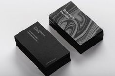 two black and white business cards sitting on top of each other