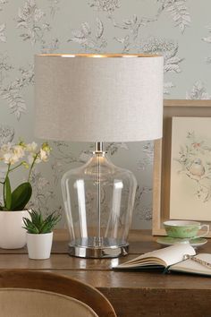 a glass table lamp sitting on top of a wooden desk