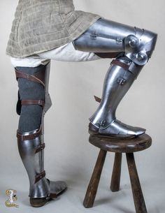 a man in armor is sitting on a stool with his foot propped against the leg