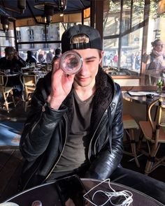 a man sitting at a table holding up a wine glass in front of his face