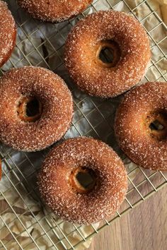 several donuts sitting on a cooling rack with powdered sugar sprinkled on them